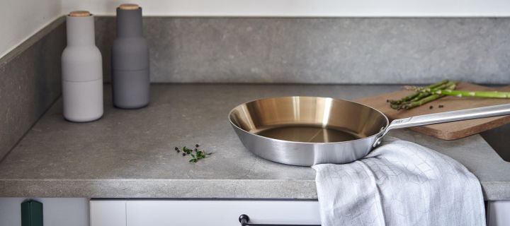 Mehr Freude am Kochen – geben Sie dem Ambiente Ihrer Küche einen eleganten Touch - hier sehen Sie die stilvolle Fiskars Bratpfanne aus Edelstahl zusammen mit dem schönen schwedischen Grace Dimma Küchentuch von Rörstrand.