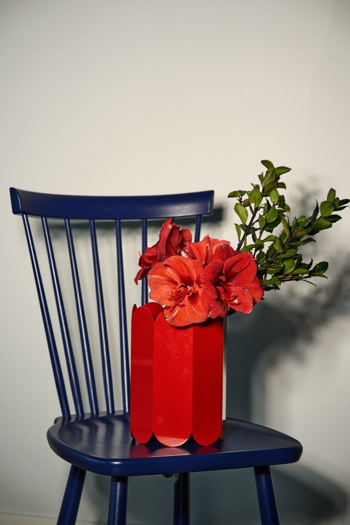Farbtrends 2024: Die Trendfarbe des Jahres ist ein sattes Rot, welches Sie hier in Form der roten Arcs-Vase von HAY auf einem dunkelblauen Lilla Åland-Stuhl von Stolab sehen.