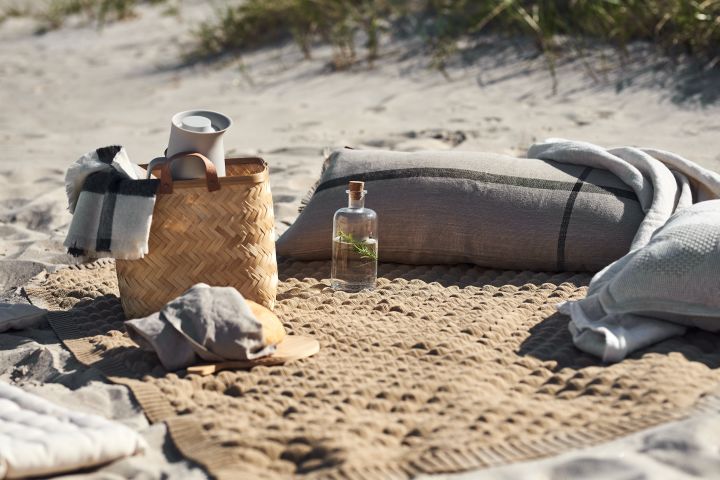 Picknick-Decke am Strand mit Korb, Kissen und Decken.