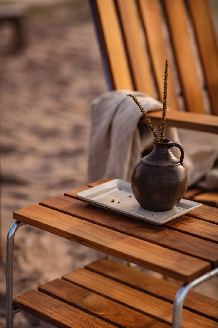 Lernen Sie Grythyttan kennen: Hier sehen Sie einen Stapel Teller auf einem Holztisch für den Außenbereich.