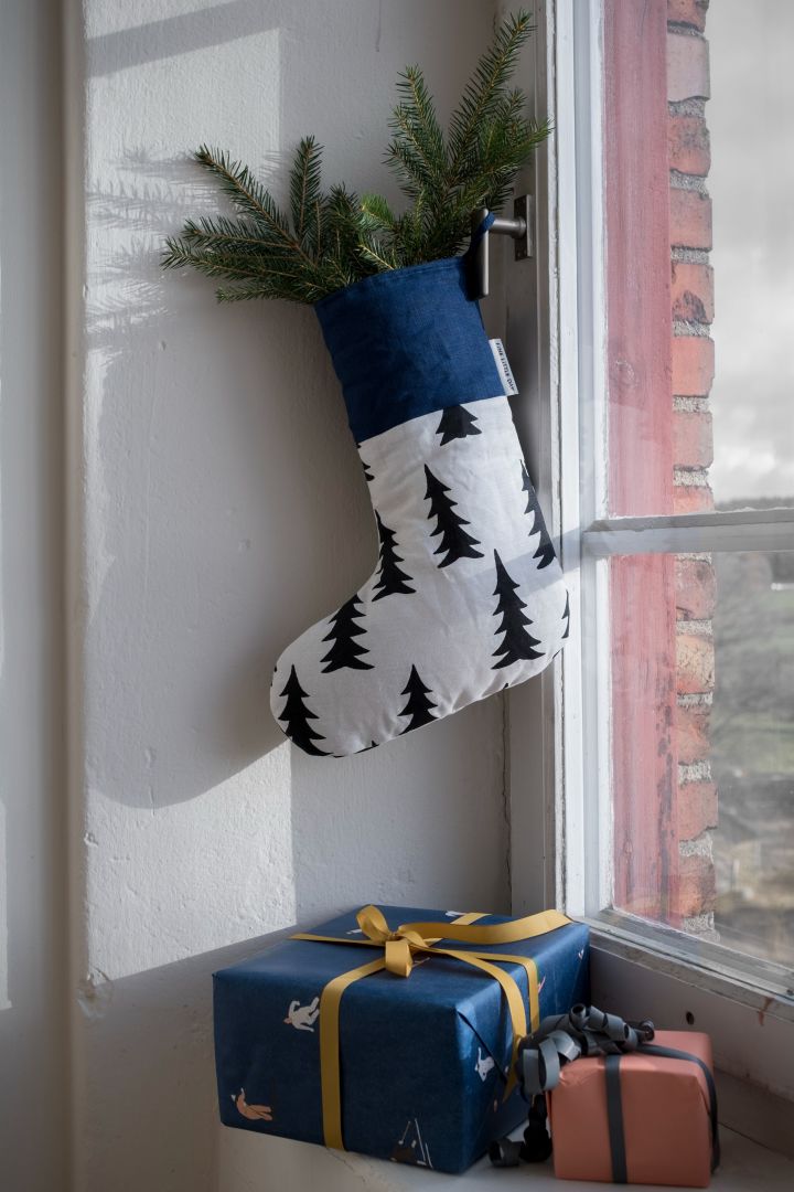 Weihnachtsdekoration basteln mit Tannengrün: Hier sehen Sie den Gran Weihnachtsstrumpf von Fine litte day, dekoriert mit Tannenzweigen, aufgehängt in einem Fenster.
