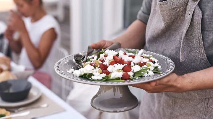 Auf dem sommerlich gedeckten Tisch wird auf einer Kuchenplatte von PotteryJo ein herrlich sommerlicher Salat mit Erdbeeren und Feta-Käse serviert. 