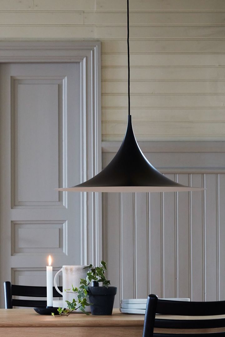 Hier sehen Sie die skandinavische Designlampe Semi von Gubi über einem Esstisch hängen.