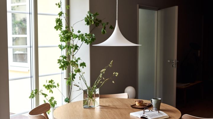 Entdecken Sie die besten Tipps von GUBI für die Beleuchtung Ihres Zuhauses. Hier sehen Sie die Semi-Pendelleuchte über einem Esstisch hängen. 