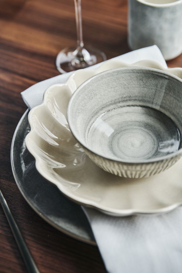 Tischgedeck mit beiger Austernschale in der Farbe Sand, grauer Schale, Teller und Becher in den Mateus-Serien Basic, MSY, Stripes und Oyster.