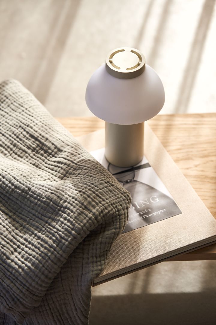 Entdecken Sie angesagte Pilzlampen: Hier sehen Sie die PC Tischleuchte von HAY auf einem Tisch mit einer grauen Decke daneben.