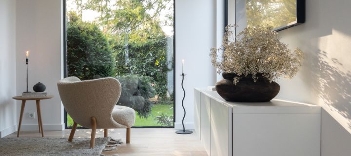 Hier sehen Sie ein Wohnzimmer im skandinavischen Stil, in welchem der Little Petra Sessel am Fenster neben dem geschwungenen Kerzenhalter von Cooee Design steht. 