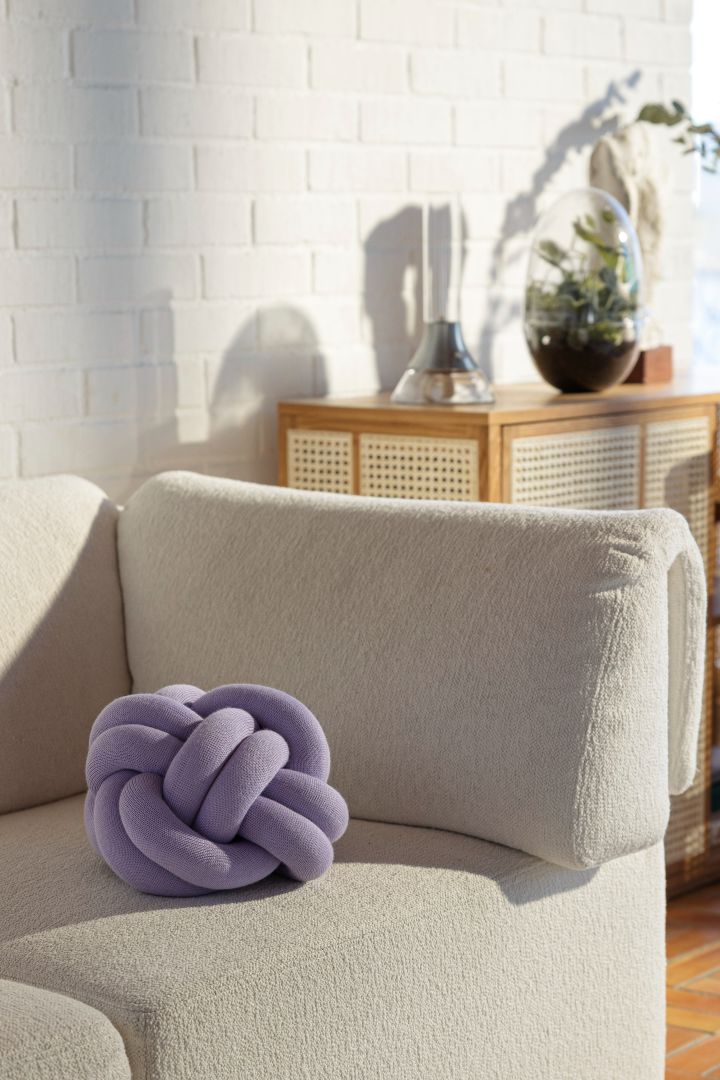 Farbtrends 2024: Zu den Trendfarben des Jahres zählt auch Lavendel. Hier sehen Sie das lavendelfarbene Knot-Kissen von Design House Stockholm auf einer beigefarbenen Couch.