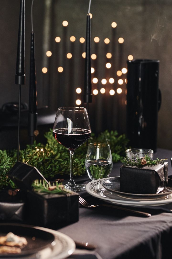 Ein dramatisch gedeckter Tisch in Schwarz ist perfekt für Halloween, kann aber auch für eine Hochzeit oder Weihnachten verwendet werden. Hier sehen Sie ein Gedeck mit schwarzen Kerzen und schwarzen Tellern von Broste Copenhagen. 